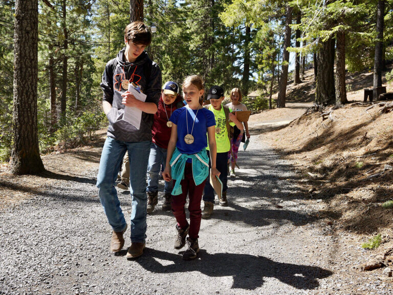 An older student leads younger students on a hike at Camp Tamarack.