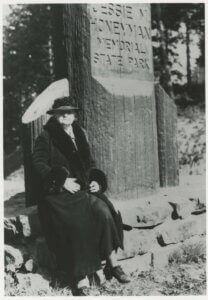 Jessie M. Honeyman, seated in front of a park sign