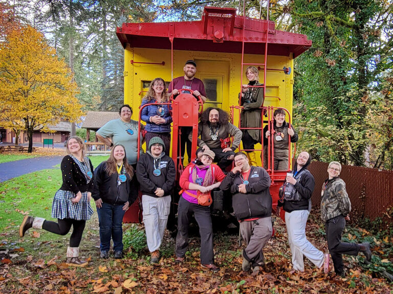 The adult camp staff assembled on the end of a yellow caboose for a group photo